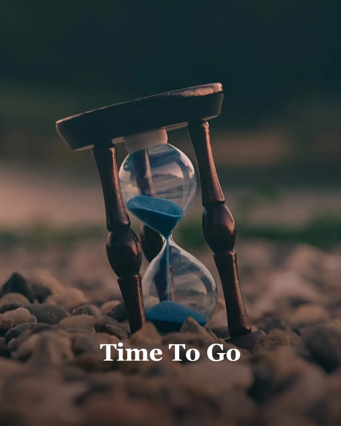 selective focus photo of brown and blue hourglass on stones