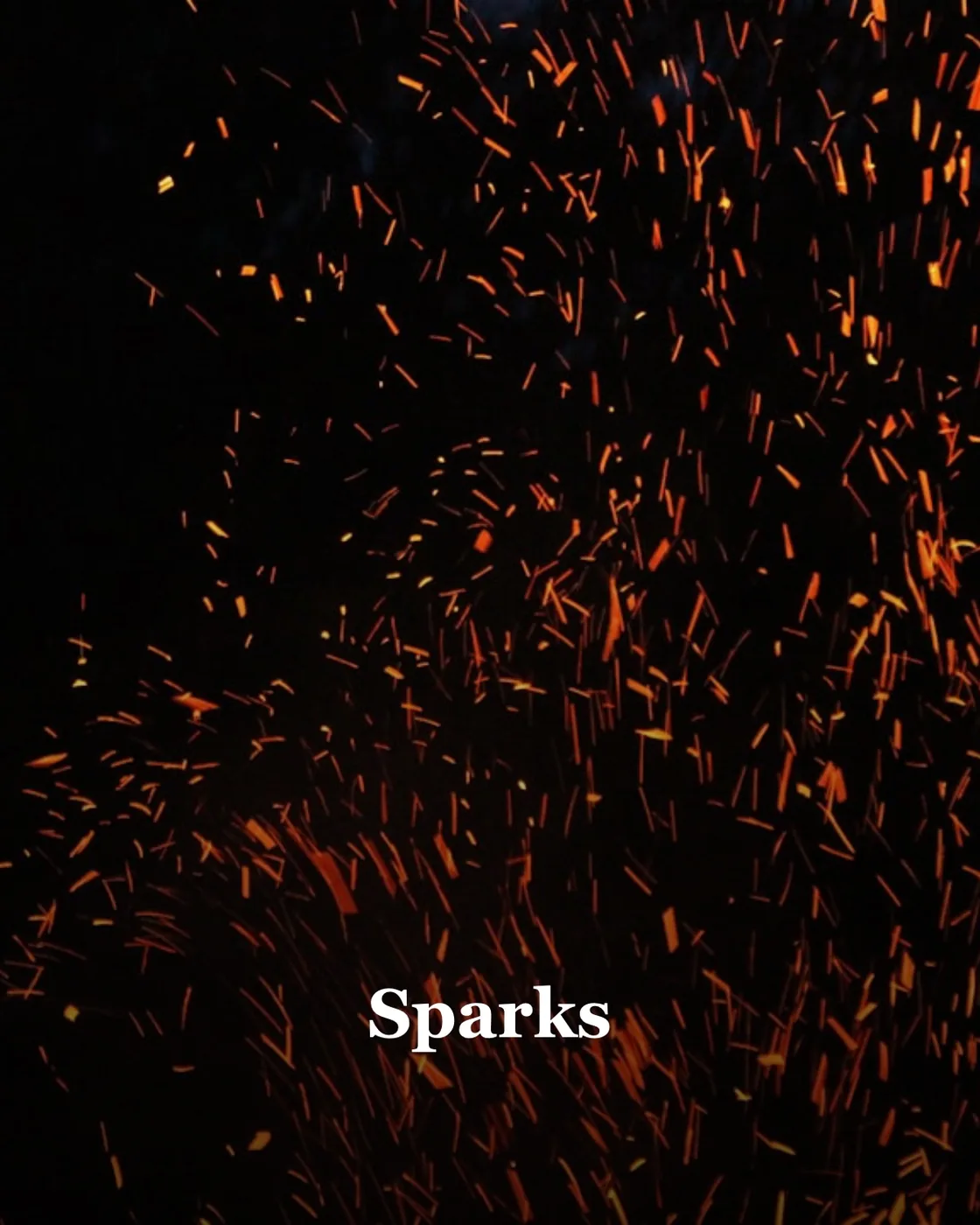 Bright orange embers rising into the dark night air from a fire
