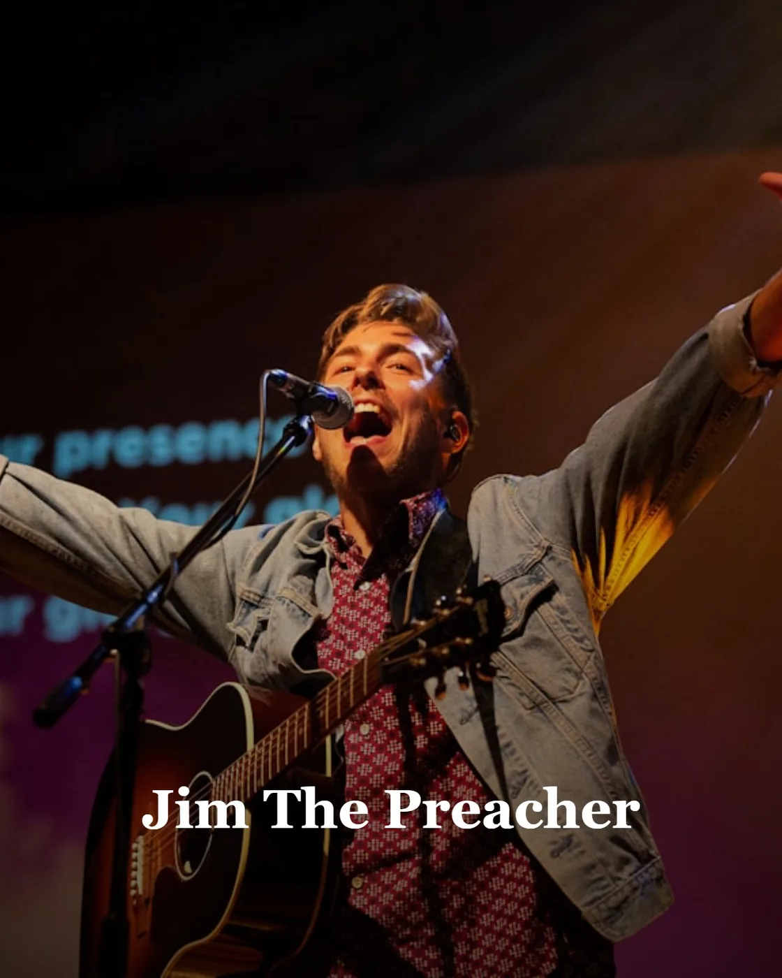a man singing into a microphone while holding a guitar